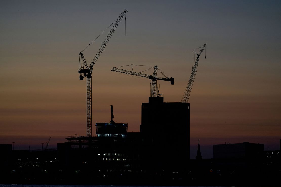 Construction cranes are silhouetted against the sky in Detroit on September 13, 2022.